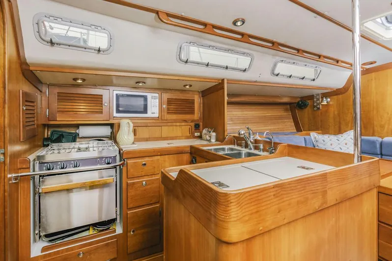 Lark Yacht Photos Pics Interior of 2001 J Boats 46 sailboat, featuring a wooden kitchen with stove, sink, and microwave.
