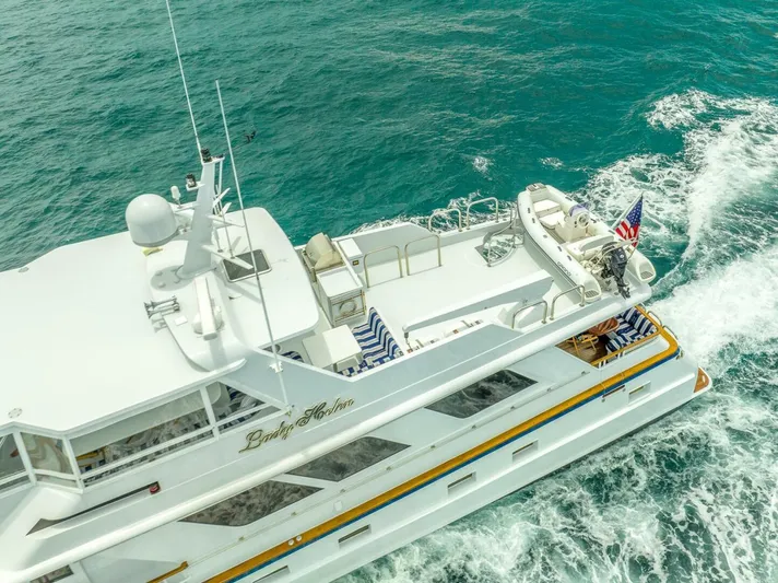 Lady Helen Yacht Photos Pics Aerial view of 1982 Broward 87 yacht cruising on turquoise waters.