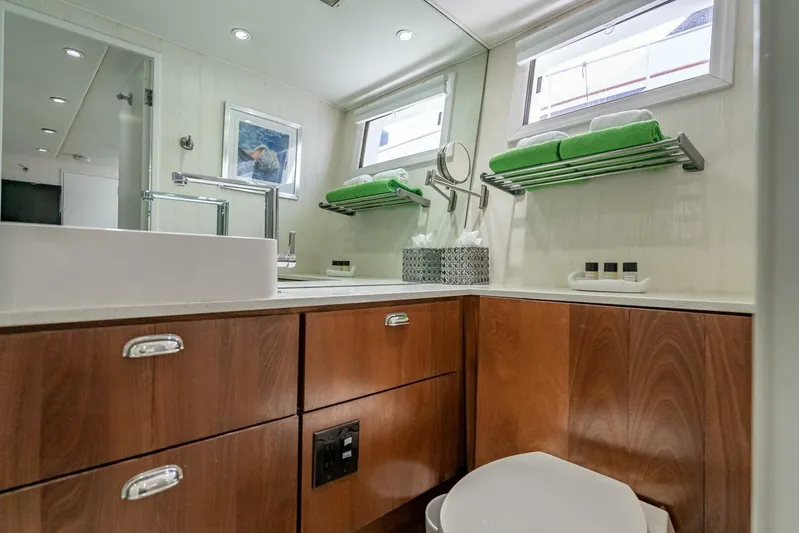 Lady Helen Yacht Photos Pics Luxurious bathroom in 1982 Broward 87 yacht with modern fixtures and wooden cabinetry.