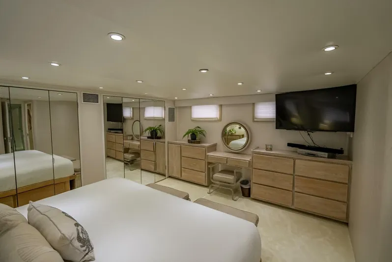 Lady Helen Yacht Photos Pics Luxurious bedroom interior on 1982 Broward 87 yacht with modern decor and mirrored walls.