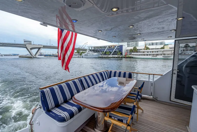 Lady Helen Yacht Photos Pics Aft deck of 1982 Broward 87 yacht with striped seating and American flag.