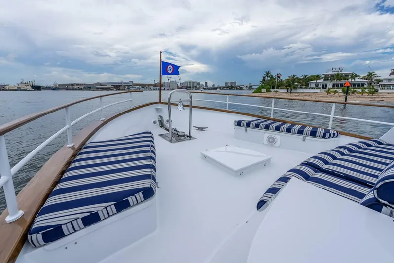 Lady Helen Yacht Photos Pics Luxurious 1982 Broward 87 yacht deck with striped lounge chairs and scenic waterfront view.