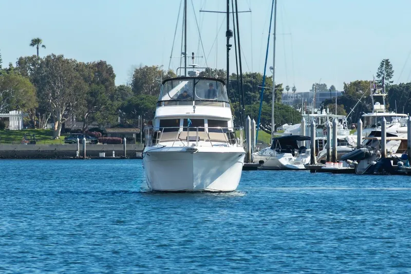 Katerina Yacht Photos Pics 1996 Navigator 5300 Classic yacht cruising in a marina, surrounded by other boats and lush greenery.