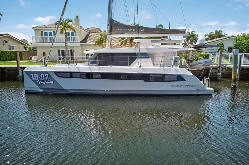 Ten-seven Freedom Yacht Photos Pics 2023 Leopard 42 catamaran "Freedom" docked by waterfront homes, sunny day.