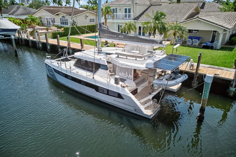 Ten-seven Freedom Yacht Photos Pics Leopard 42 catamaran docked by waterfront homes, featuring solar panels, 2023 model.
