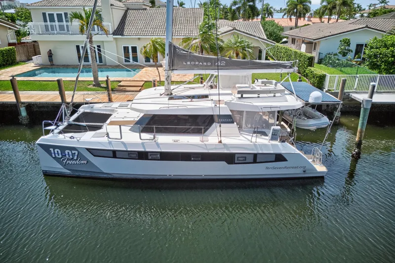 Ten-seven Freedom Yacht Photos Pics 2023 Leopard 42 catamaran docked by waterfront homes, featuring sleek design and modern amenities.