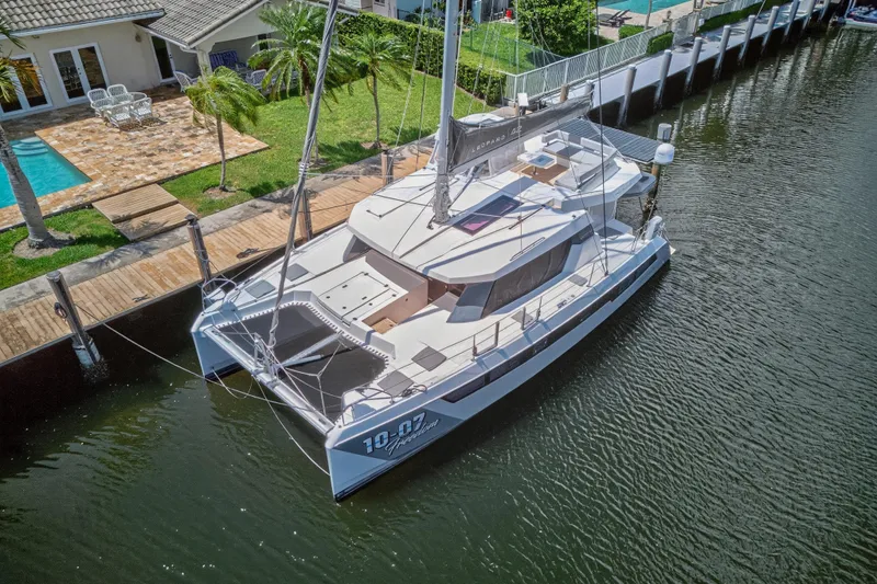 Ten-seven Freedom Yacht Photos Pics 2023 Leopard 42 catamaran docked by a waterfront home with a pool.