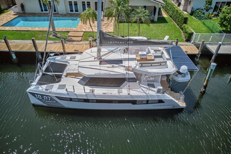 Ten-seven Freedom Yacht Photos Pics Aerial view of 2023 Leopard 42 catamaran docked by a waterfront home.