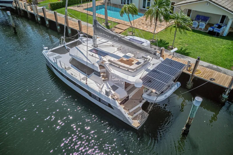 Ten-seven Freedom Yacht Photos Pics 2023 Leopard 42 catamaran docked by a waterfront home with solar panels.