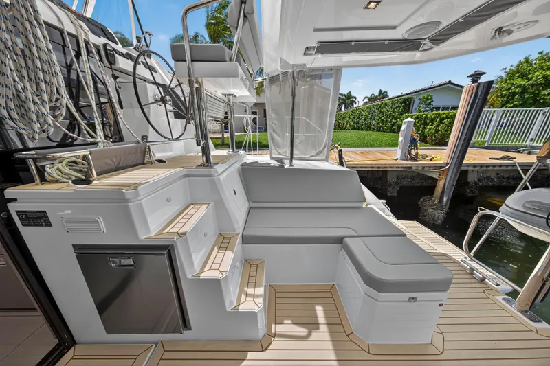 Ten-seven Freedom Yacht Photos Pics 2023 Leopard 42 yacht deck with seating, steps, and helm, docked by a waterfront.