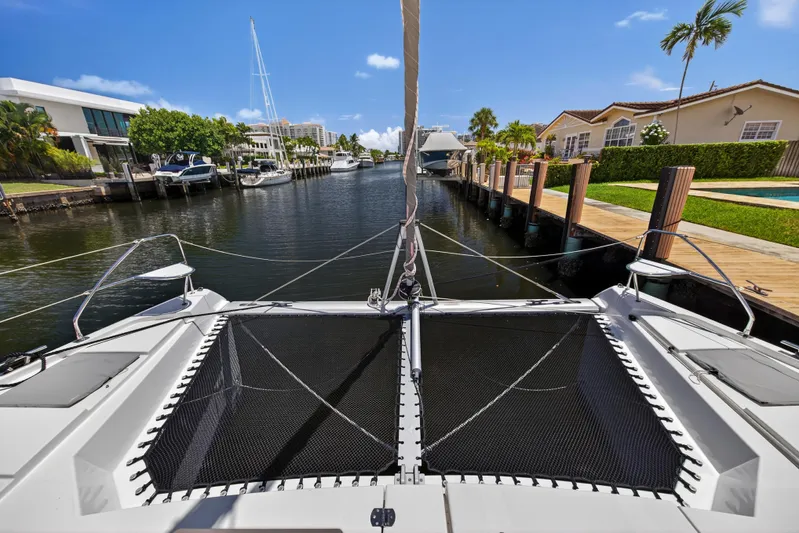 Ten-seven Freedom Yacht Photos Pics Front view of 2023 Leopard 42 catamaran docked in a scenic canal setting.
