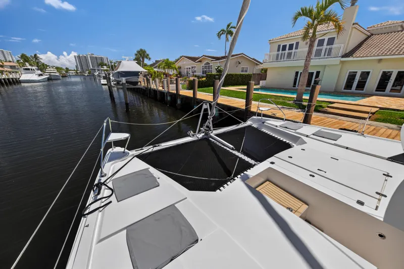 Ten-seven Freedom Yacht Photos Pics 2023 Leopard 42 catamaran docked by waterfront homes under a clear blue sky.