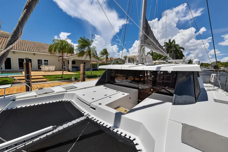Ten-seven Freedom Yacht Photos Pics 2023 Leopard 42 catamaran docked by a waterfront home, under a clear blue sky.