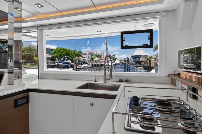 Ten-seven Freedom Yacht Photos Pics Modern kitchen interior on 2023 Leopard 42 yacht with marina view through large window.