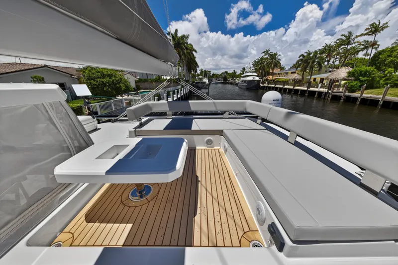 Ten-seven Freedom Yacht Photos Pics Luxurious 2023 Leopard 42 yacht deck with seating and table, docked by a scenic canal.