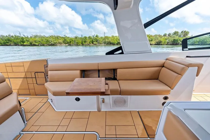  Yacht Photos Pics 2022 Aviara AV40 OB boat interior with tan seating and wooden table, scenic water view.