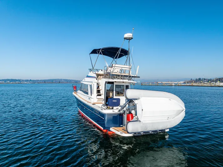 Awol Yacht Photos Pics 2016 Cutwater 30 Command Bridge boat on calm water, featuring a dinghy and clear blue sky.