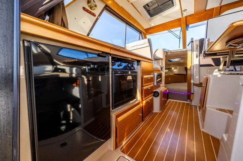 Awol Yacht Photos Pics Interior of 2016 Cutwater 30 Command Bridge with modern kitchen and wood flooring.