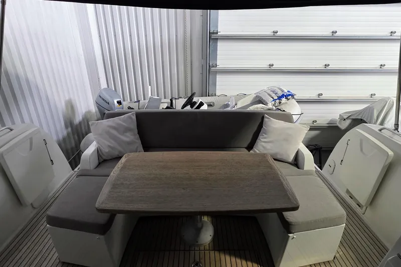 Yacht Photos Pics 2014 Jeanneau NC 14 boat interior with cushioned seating and wooden table.
