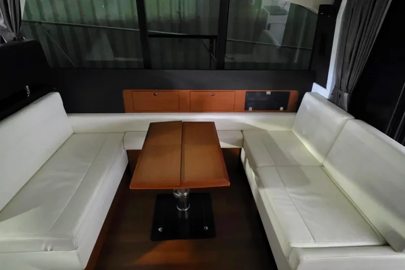  Yacht Photos Pics Interior of 2014 Jeanneau NC 14 yacht with white seating and wooden table.