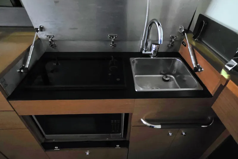  Yacht Photos Pics Compact kitchen area in a 2014 Jeanneau NC 14 boat, featuring a sink and stovetop.