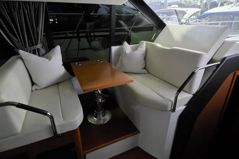  Yacht Photos Pics 2014 Jeanneau NC 14 interior with white seating, wooden table, and large windows.