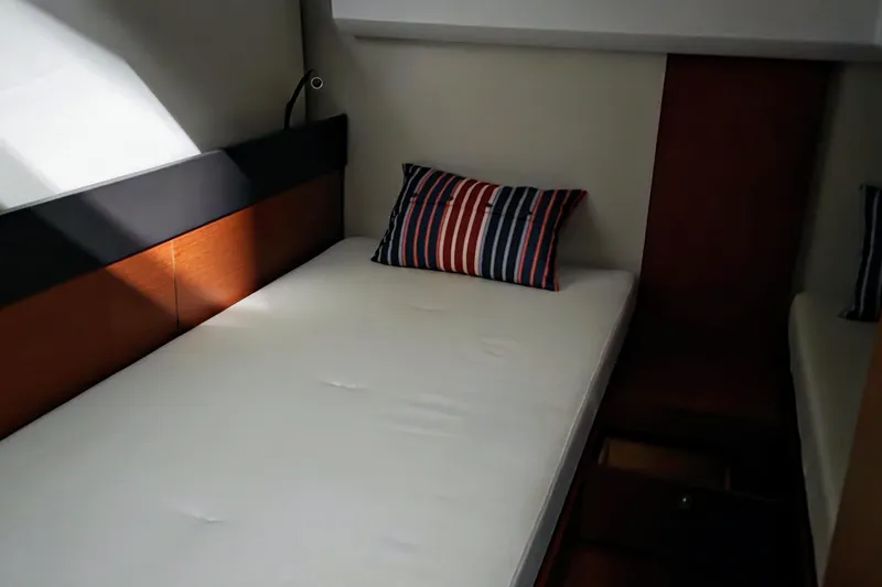  Yacht Photos Pics Cozy cabin interior of 2014 Jeanneau NC 14 with striped pillow and wooden accents.