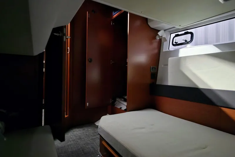  Yacht Photos Pics 2014 Jeanneau NC 14 cabin interior with bed, wooden cabinetry, and window.