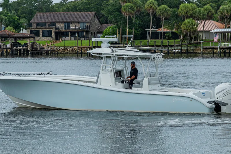  Yacht Photos Pics 2018 Yellowfin 36 Offshore boat cruising on a calm river near waterfront homes.
