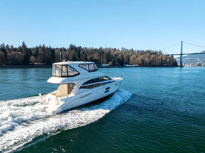  Yacht Photos Pics 2014 Meridian 441 Sedan cruising on a scenic waterway with a bridge in the background.