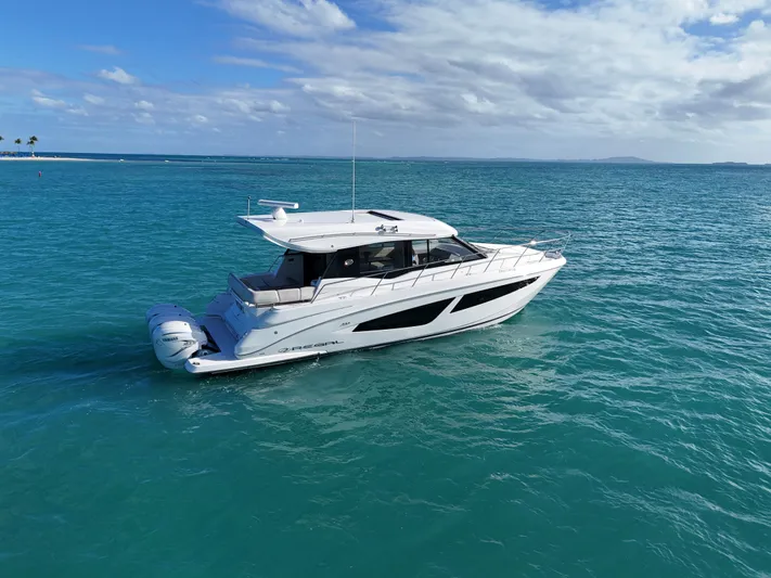  Yacht Photos Pics 2022 Regal 42 XO yacht cruising on turquoise ocean waters under a partly cloudy sky.