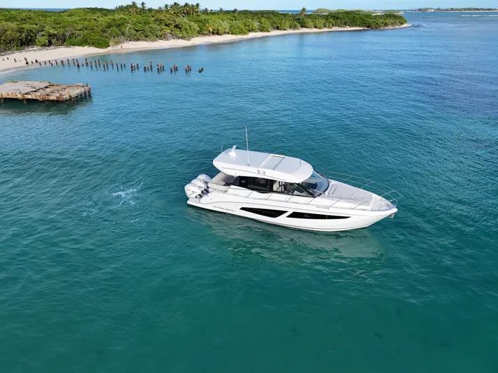  Yacht Photos Pics 2022 Regal 42 XO yacht cruising in clear blue waters near a tropical island.