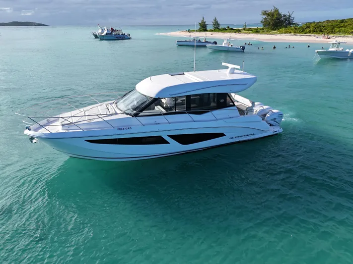  Yacht Photos Pics 2022 Regal 42 XO yacht cruising in clear turquoise waters near a sandy beach.