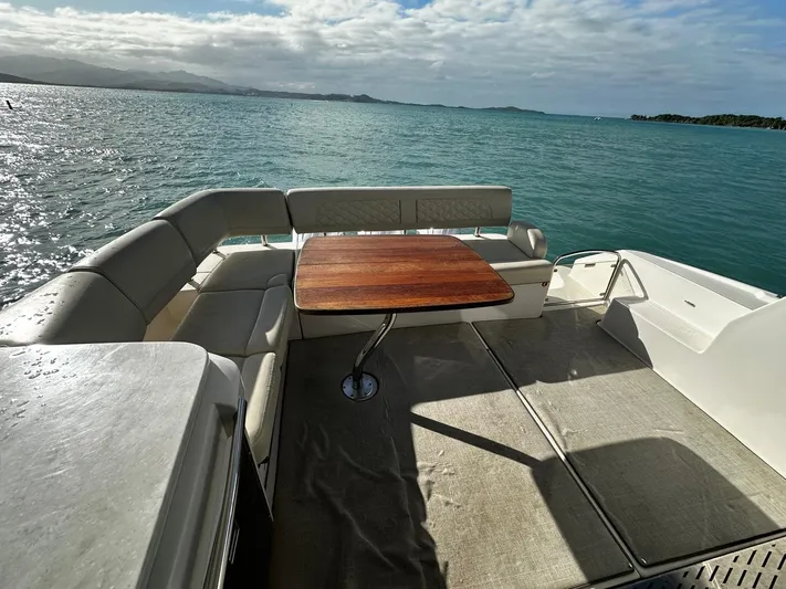  Yacht Photos Pics 2022 Regal 42 XO yacht deck with seating and table, overlooking serene ocean waters.
