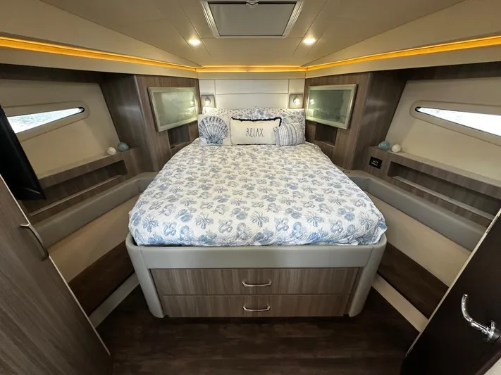  Yacht Photos Pics Luxurious bedroom interior of 2022 Regal 42 XO yacht with cozy bedding and ambient lighting.