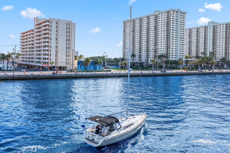 Americana Yacht Photos Pics 2014 Beneteau Oceanis 37 sailboat on blue water near urban waterfront buildings.