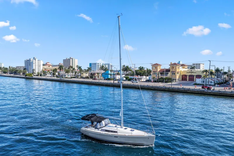 Americana Yacht Photos Pics 2014 Beneteau Oceanis 37 sailboat cruising near urban waterfront under blue sky.