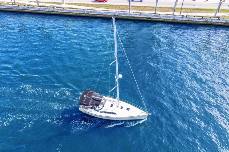 Americana Yacht Photos Pics Aerial view of 2014 Beneteau Oceanis 37 sailboat cruising in blue waters near a shoreline.