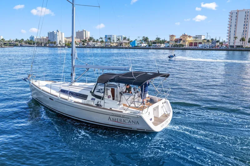 Americana Yacht Photos Pics 2014 Beneteau Oceanis 37 sailboat cruising near a city waterfront.
