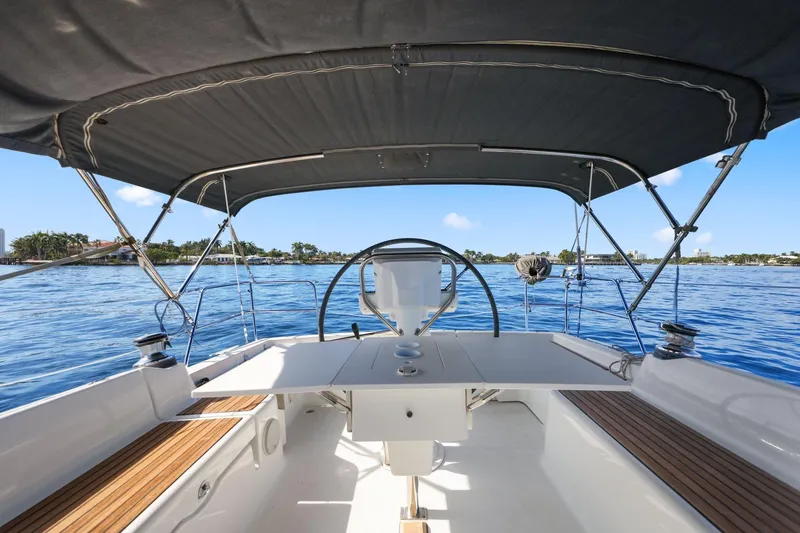 Americana Yacht Photos Pics 2014 Beneteau Oceanis 37 sailboat cockpit with canopy, steering wheel, and ocean view.