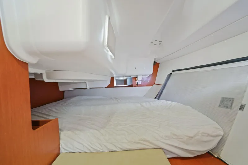 Americana Yacht Photos Pics Interior cabin of 2014 Beneteau Oceanis 37 sailboat, featuring a cozy bed and wooden accents.