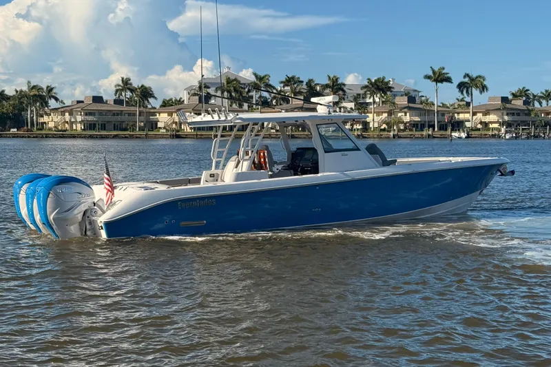  Yacht Photos Pics 2023 Everglades 395 Center Console boat cruising on a sunny day, with palm trees in the background.