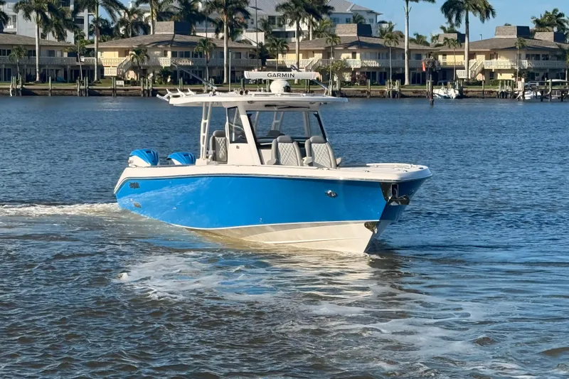  Yacht Photos Pics 2023 Everglades 395 Center Console boat cruising on a sunny waterfront.