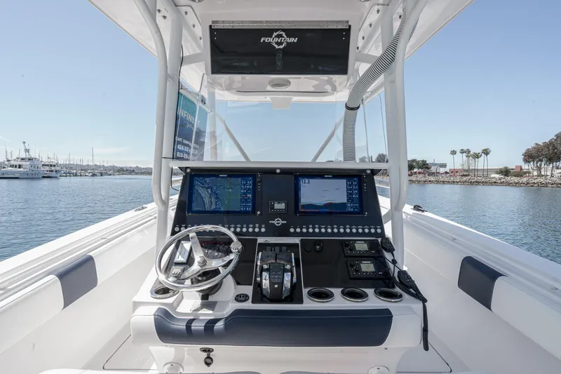 Go Time Yacht Photos Pics 2019 Fountain 38 CC boat dashboard with navigation screens and steering wheel, docked in a marina.