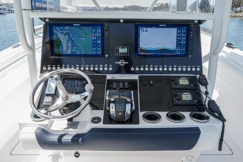 Go Time Yacht Photos Pics Control panel of a 2019 Fountain 38 CC boat with navigation screens and steering wheel.