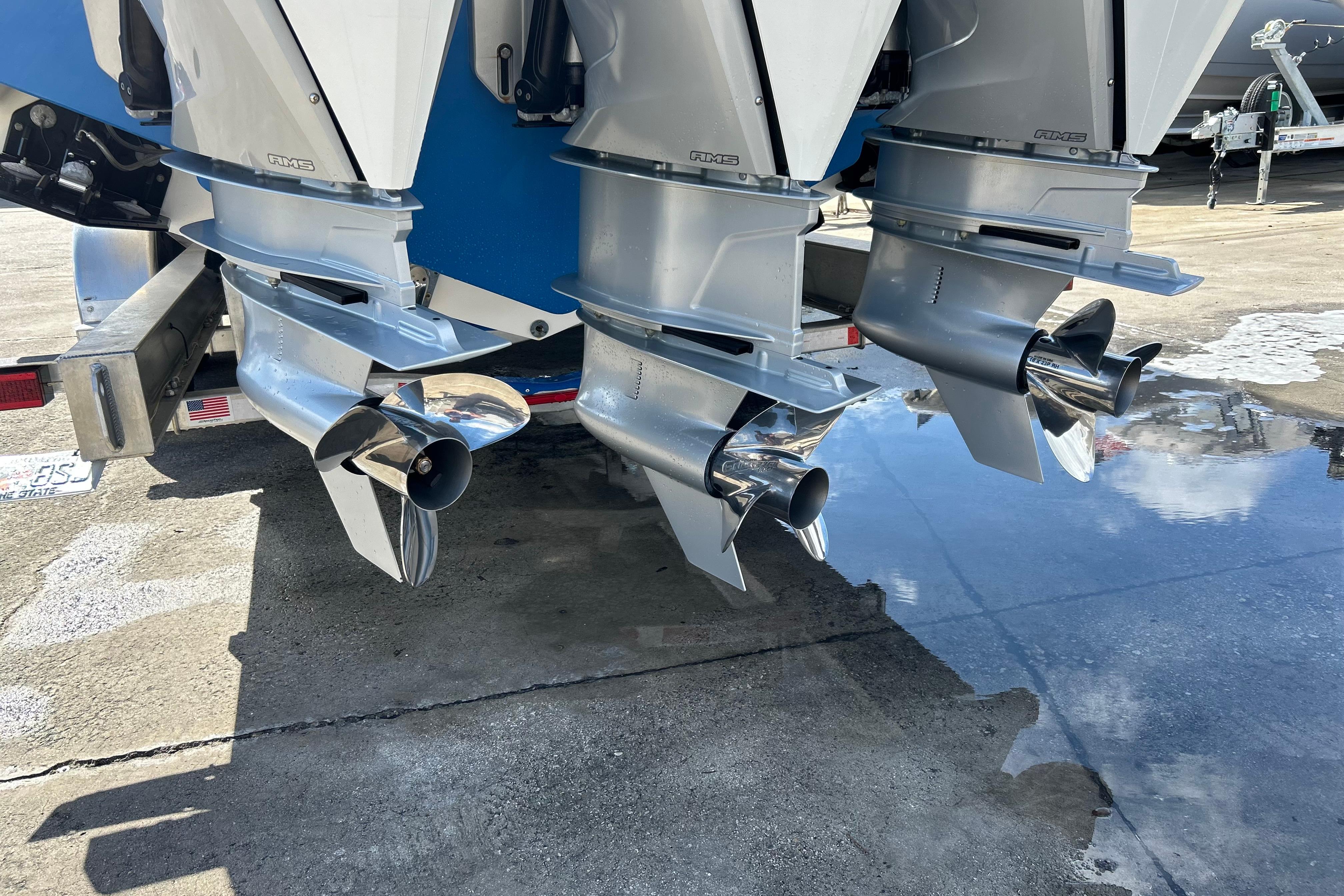 Triple outboard motors on a 2025 Contender 35 ST boat, reflecting on wet pavement.