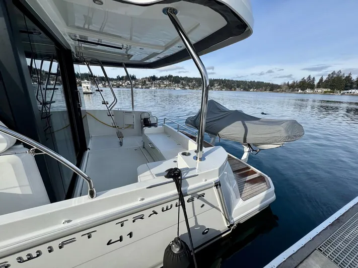 Freedom Yacht Photos Pics 2022 Beneteau Swift Trawler 41 Fly docked, showcasing spacious deck and scenic waterfront.