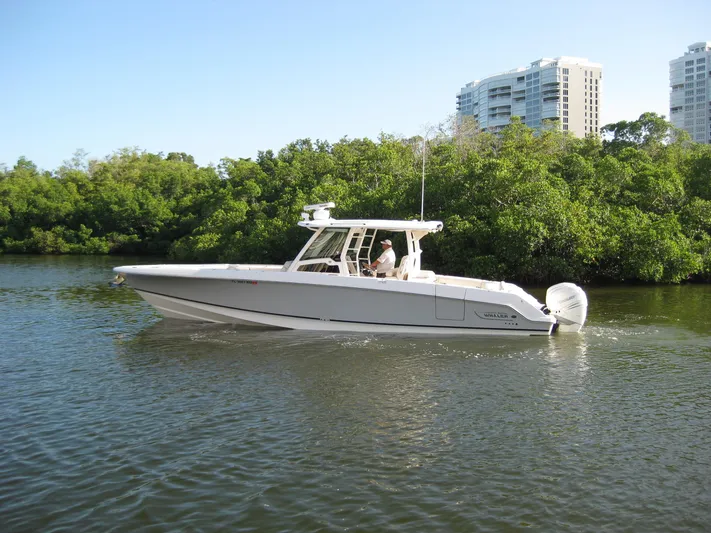  Yacht Photos Pics 2018 Boston Whaler 380 Outrage boat cruising on a calm river near lush greenery.