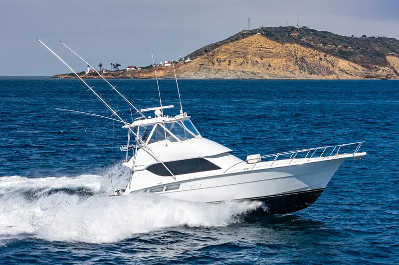 Whiplash II Yacht Photos Pics 2006 Hatteras 50 Convertible yacht cruising near a rocky island.