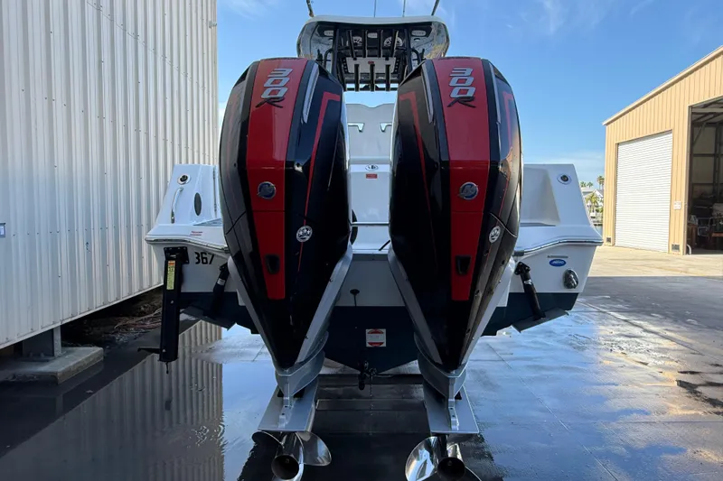  Yacht Photos Pics 2022 Tidewater 292 CC Adventure boat with dual 300 horsepower engines, docked near a warehouse.